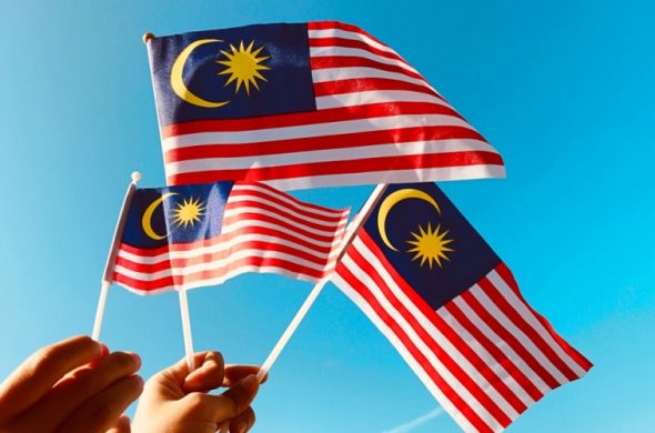 マレーシアの国旗を手で持っている