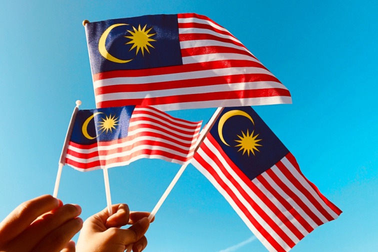 マレーシアの国旗を手で持っている