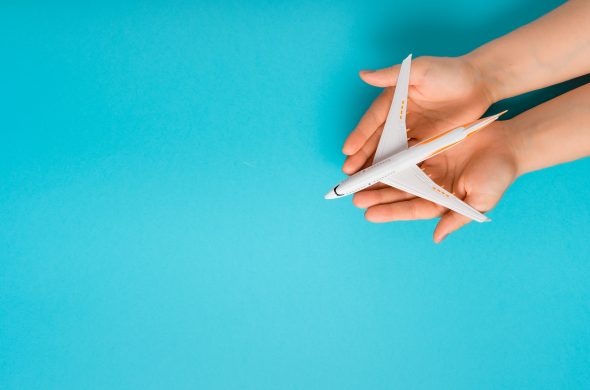 Hand carefully holding model plane. Airplane on blue color backg