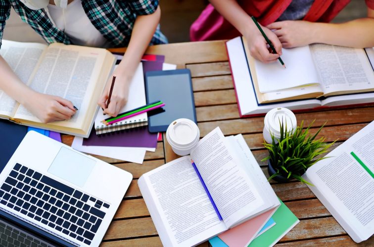 Top view of young students with books and notes in cafe