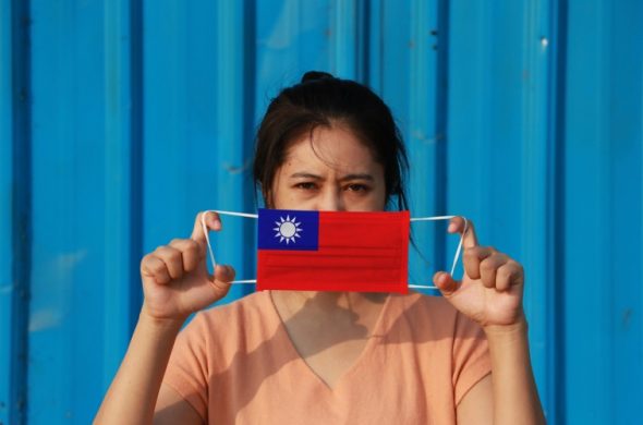 台湾の国旗の柄マスクをもったアジア女性