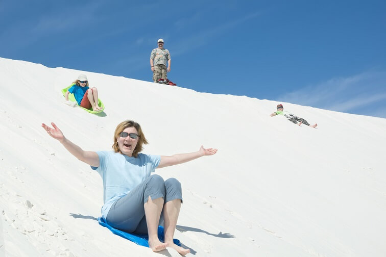 ホワイトサンズ国立公園の真っ白な砂丘の上でそり滑りを楽しむ様子