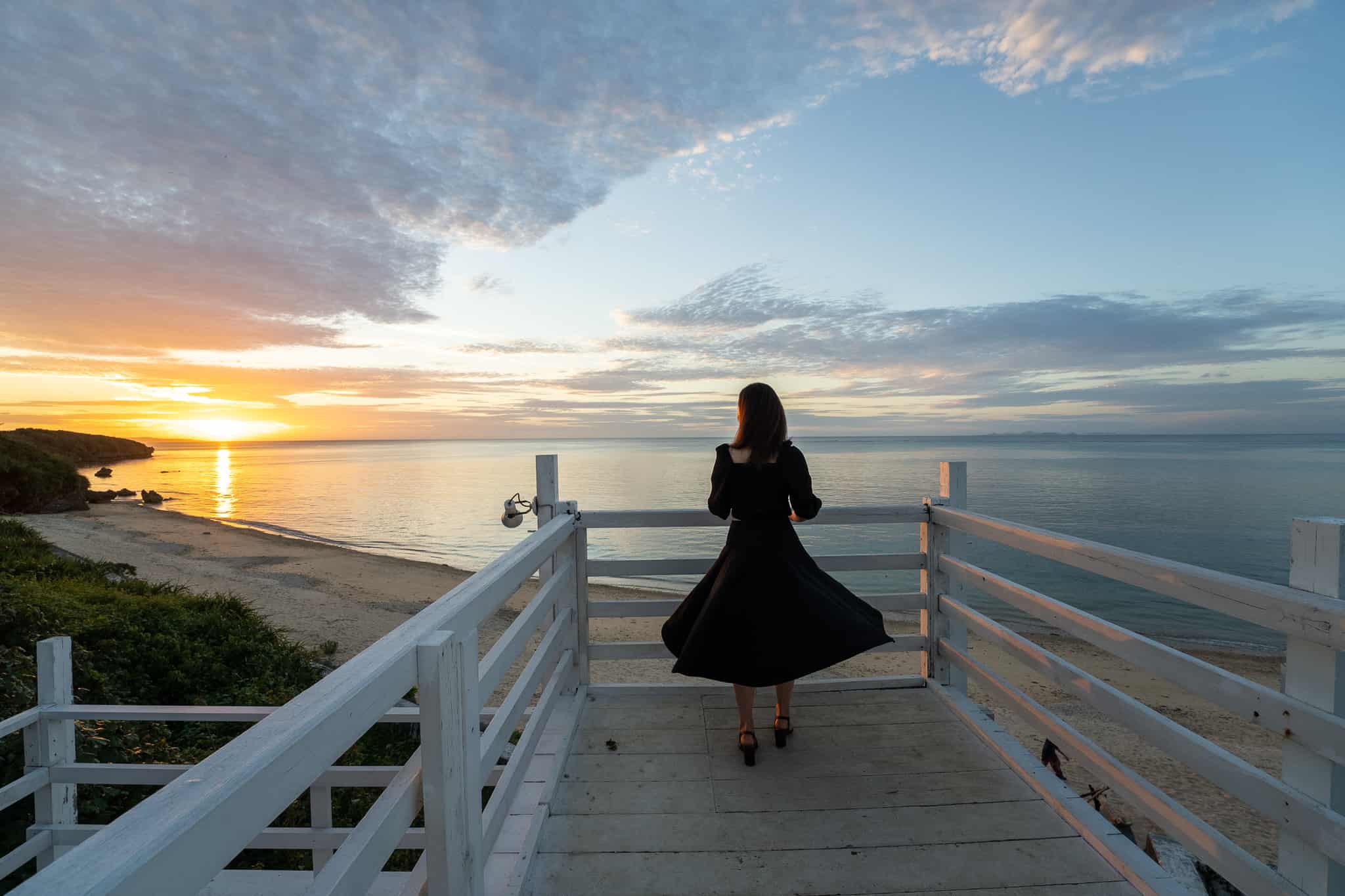 ウッドペッカー今帰仁で夕日をみる女性