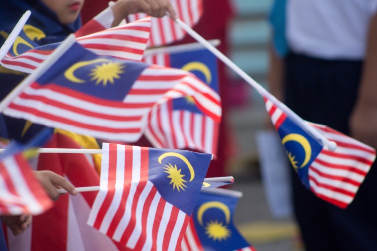 独立記念日「メルデカ」でマレーシアの国旗を振る人々